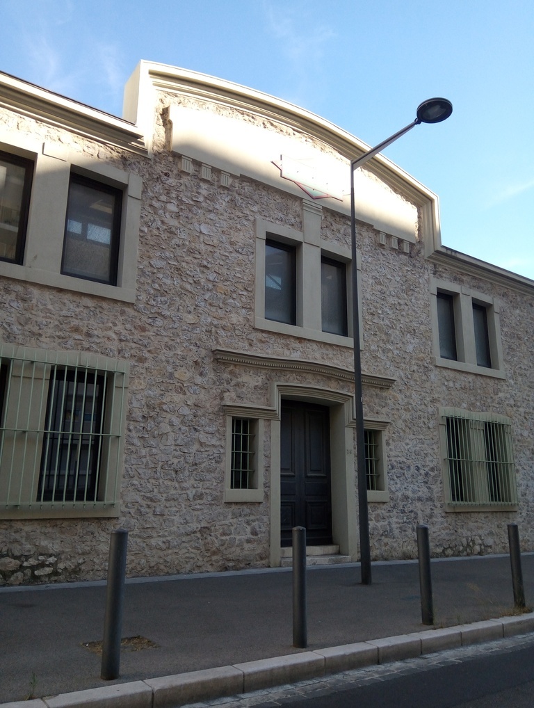 Une étonnante façade de bâtiment donnant sur la rue avec un lampadaire dans l'axe de la porte d'entrée...